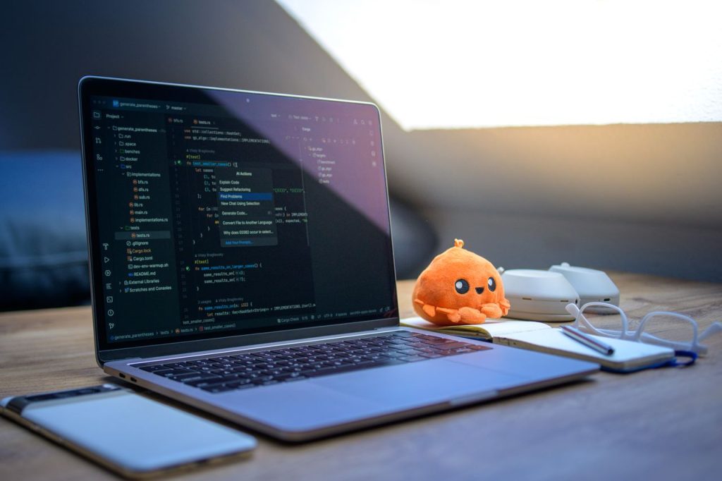 Mastering the First Impression: Your intriguing post title goes here A cozy workspace featuring a laptop displaying code, a smartphone, and a cute orange plush toy on the desk.