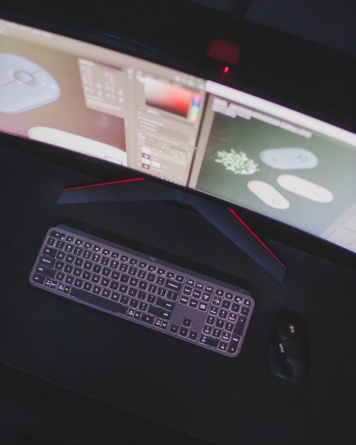 Modern computer setup featuring keyboard, mouse, and curved monitor displaying digital design software.
